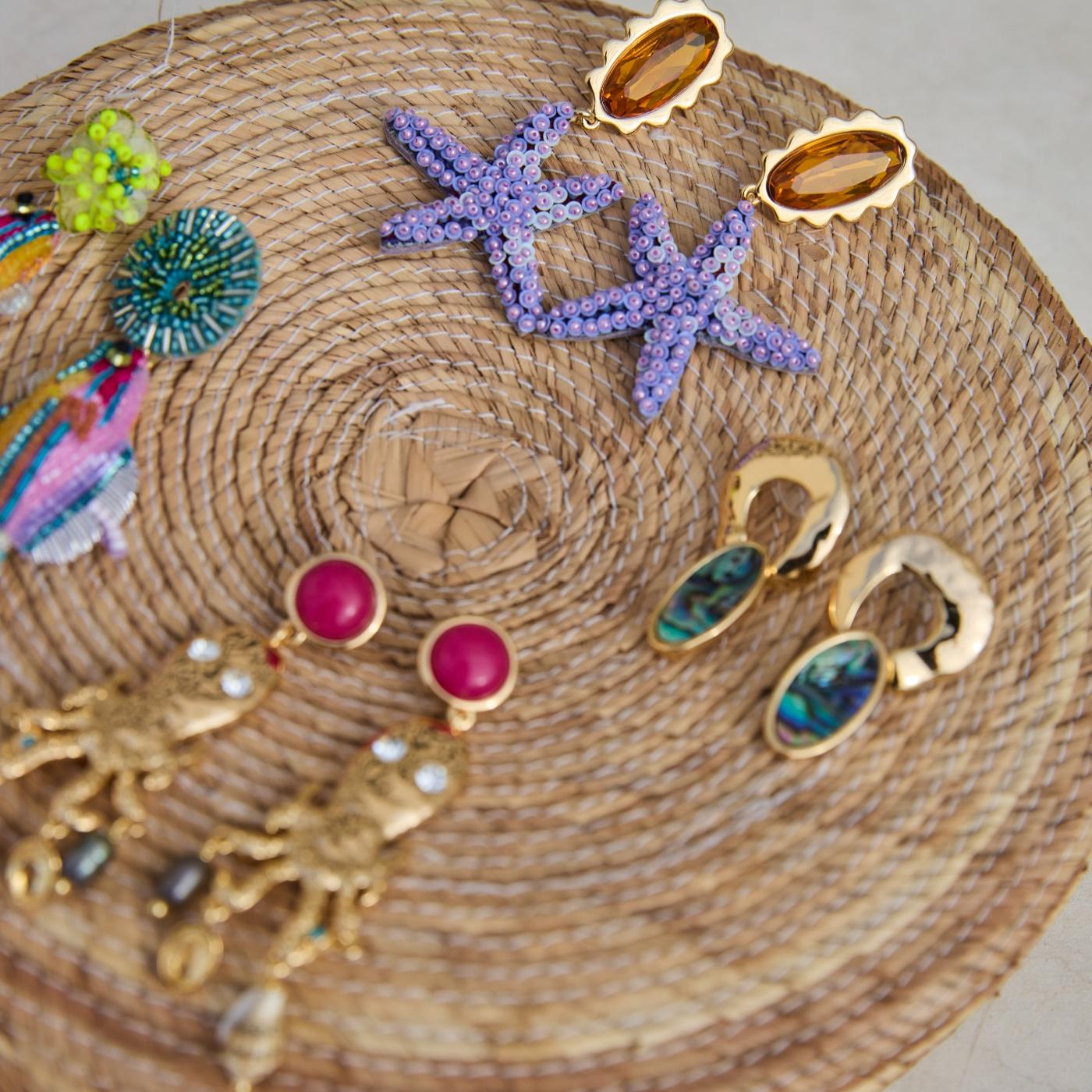 Collection of colorful earrings on a woven surface