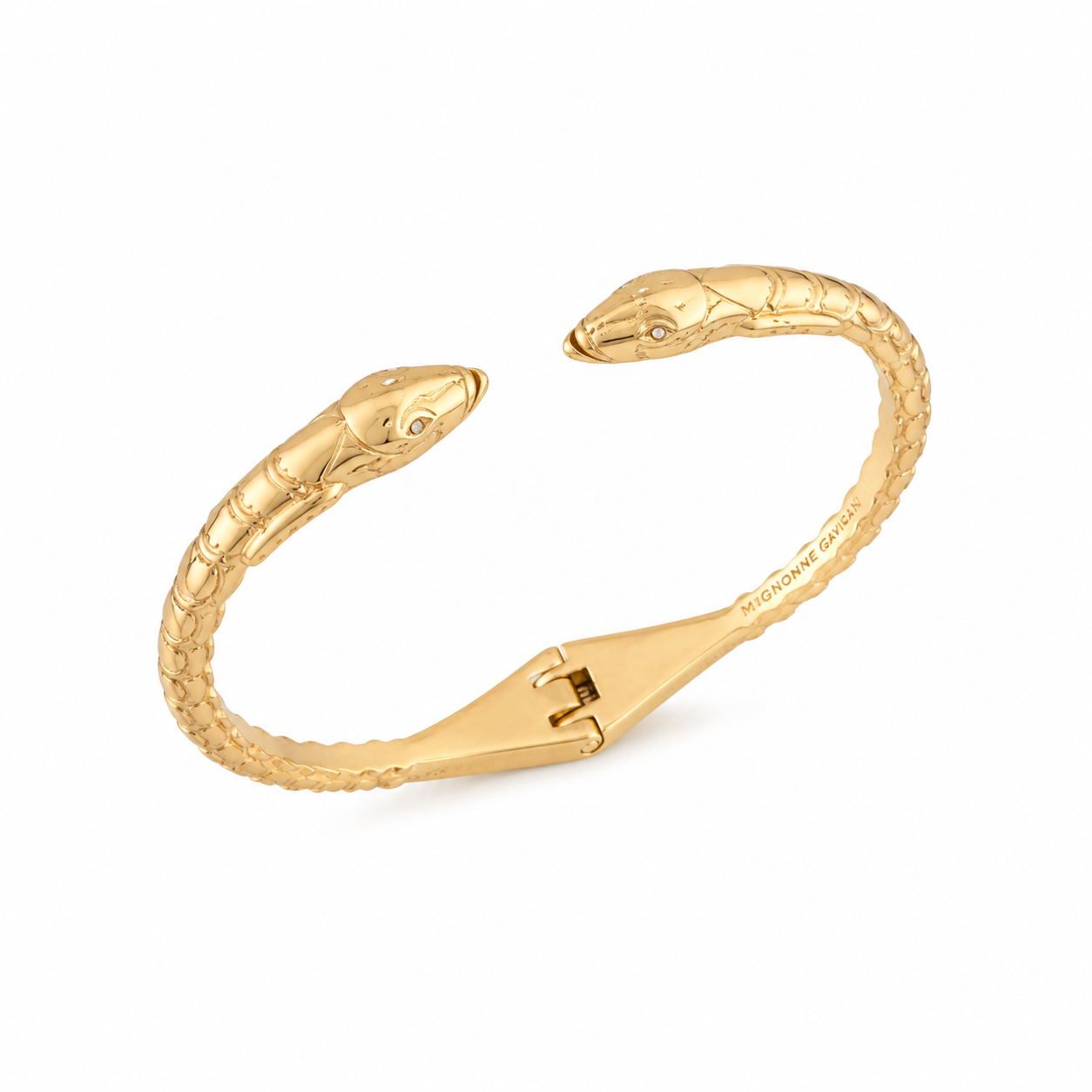 A gold snake-head bangle bracelet on a clean white background. The open cuff is designed like two snakes facing each other, with detailed scales and a small dark stone for each eye.