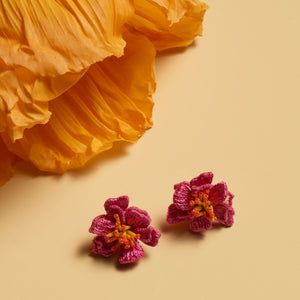 Pink and Orange Flower Stud Earrings Staged With Orange Flower Petals on Flat Cream Background