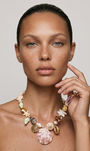 Model wearing large shell charm necklace against a whitebackground