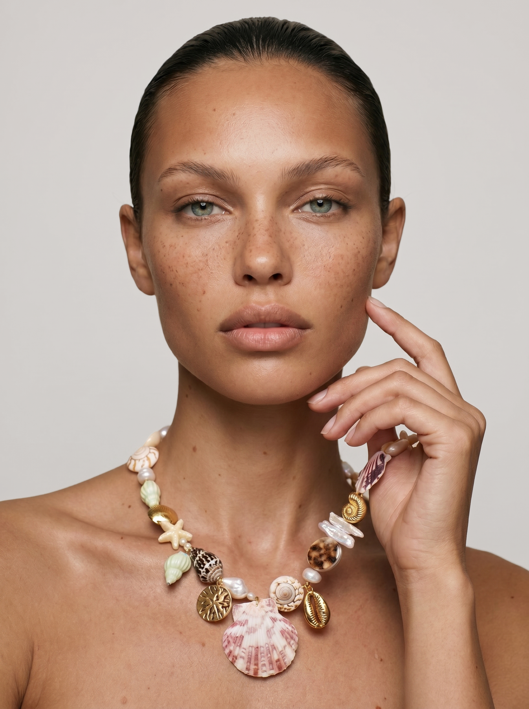 Model wearing large shell charm necklace against a whitebackground