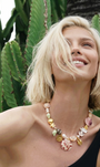 Model wearing black tank top shirt with large shell charm necklace with cactus in the background