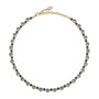 Delicate necklace featuring a strand of small blue beads and a gold-tone clasp styled on white