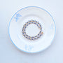 Delicate necklace featuring a strand of small blue beads and a gold-tone clasp styled on a plate