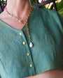Gold chain necklace with a pendant on a person wearing a green shirt.