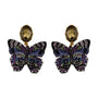 Multicolor butterfly-shaped statement earrings featuring purple, blue, and green beadwork with gold-tone details on white