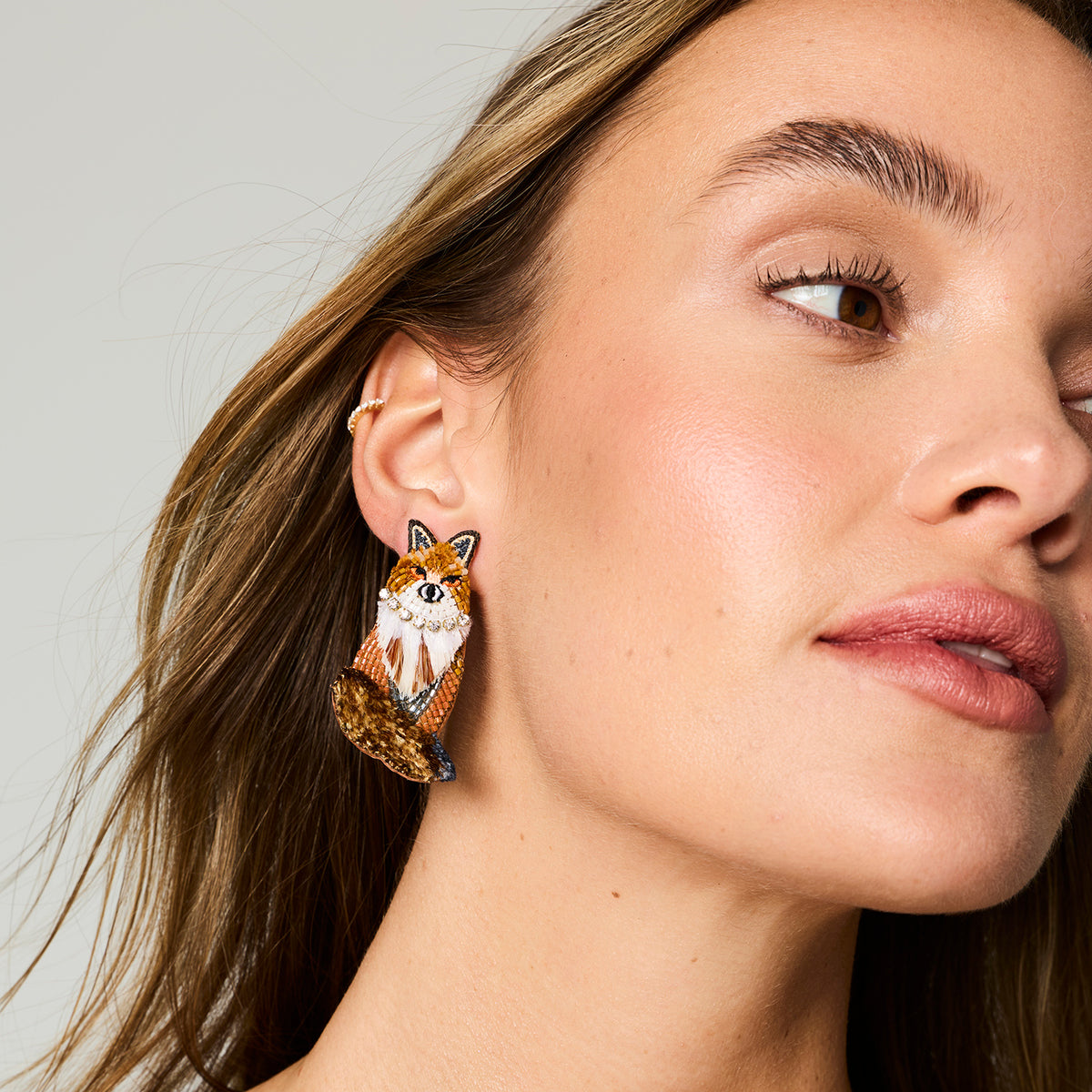 Model wearing fox embroidered and beaded earrings against a white background