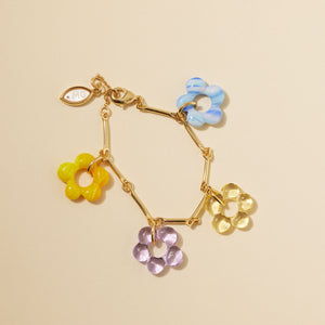 Glass Charm Bracelet with Gold Chain on Flat Tan Background