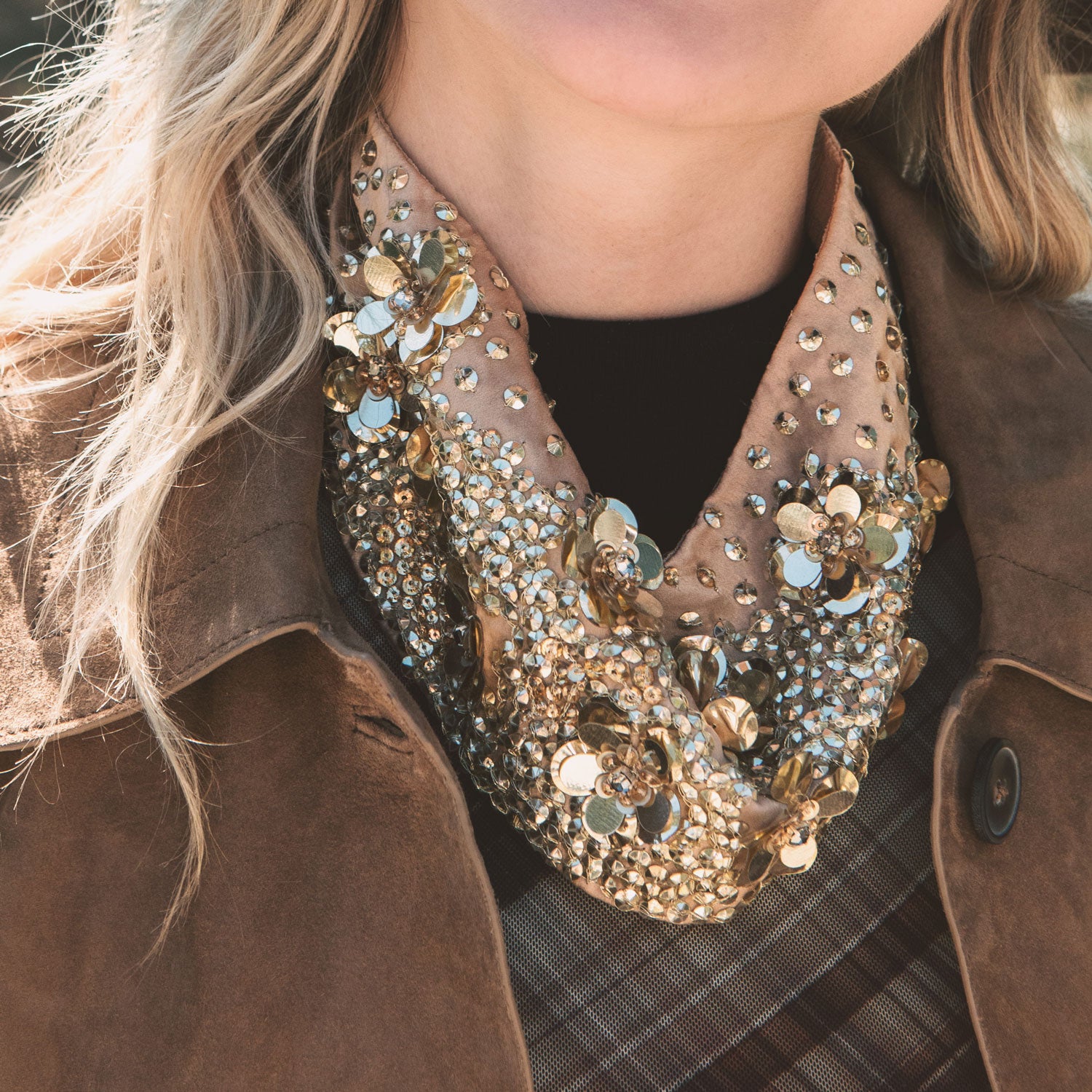 Close-up of a person wearing a decorative scarf with gold and silver embellishments.
