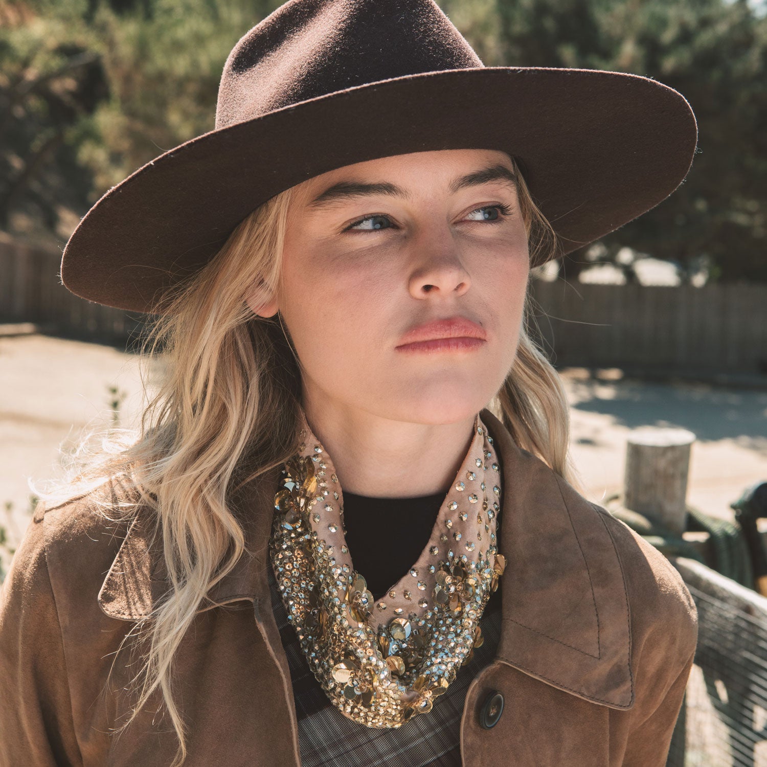 Woman wearing a brown hat and coat with a decorative scarf outdoors