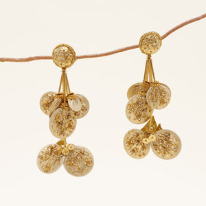 Gold Beaded Drop Earrings on Branch with Cream Background