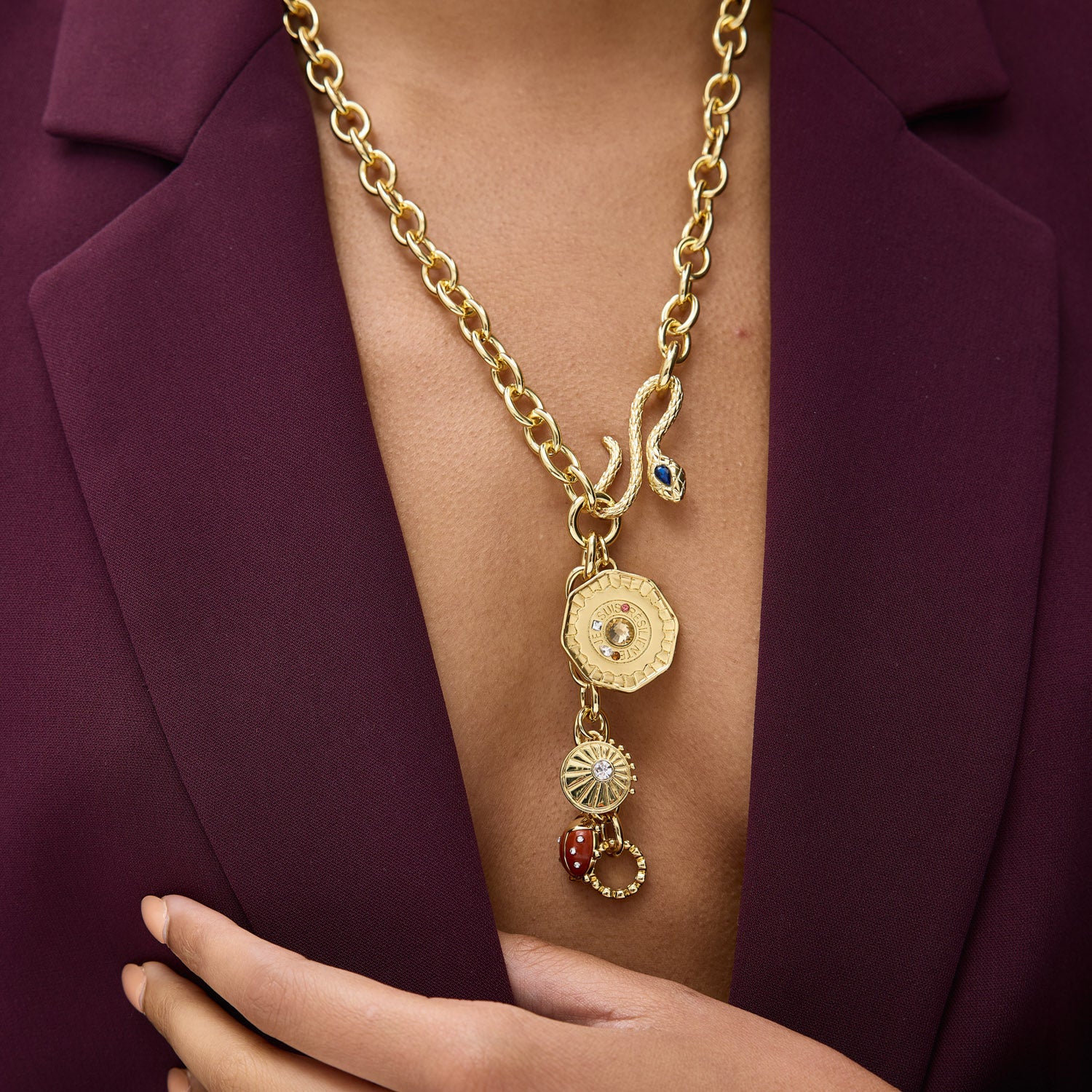 Gold necklace with charms worn by a person in a purple blazer