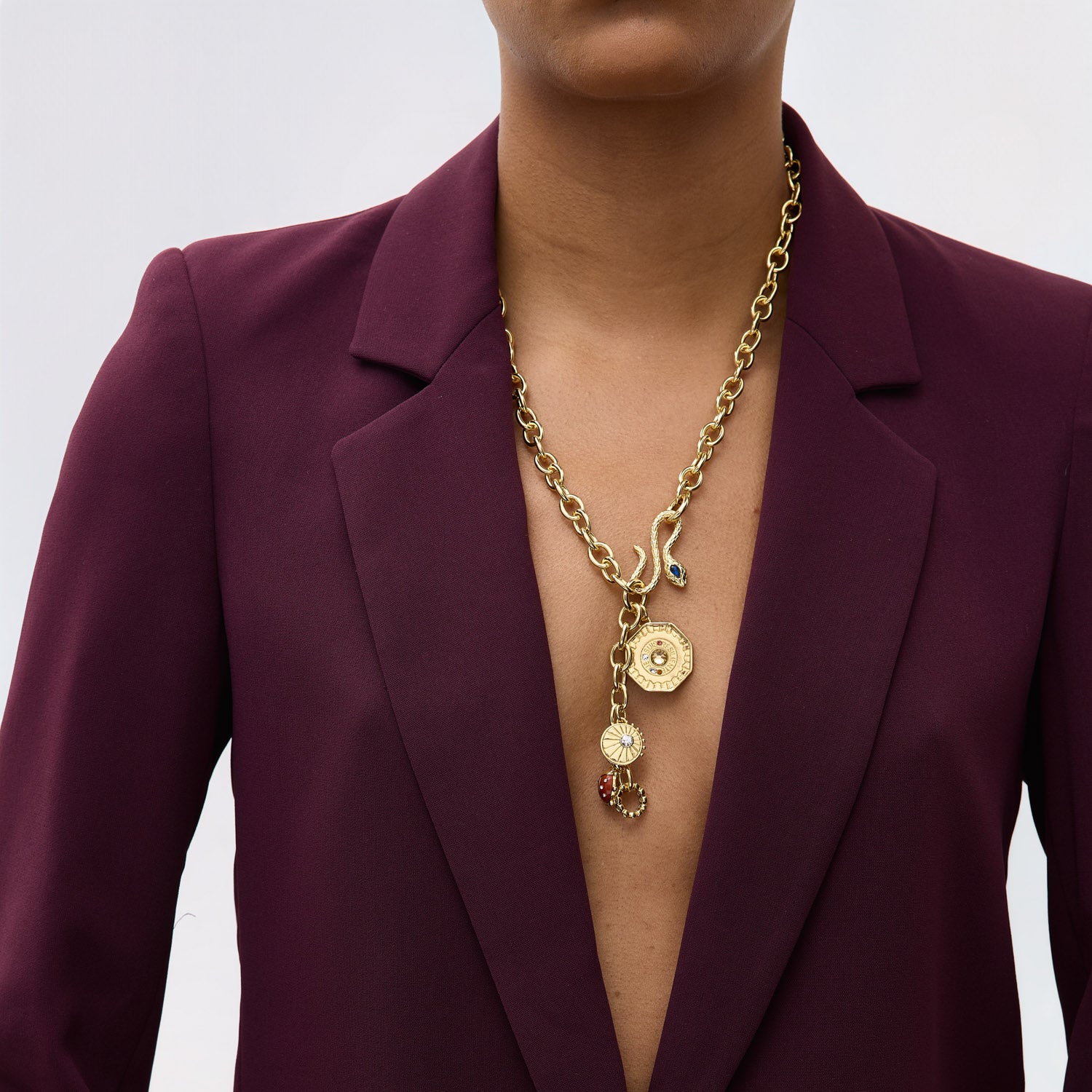Person wearing a gold necklace with a deep neckline on a plain background