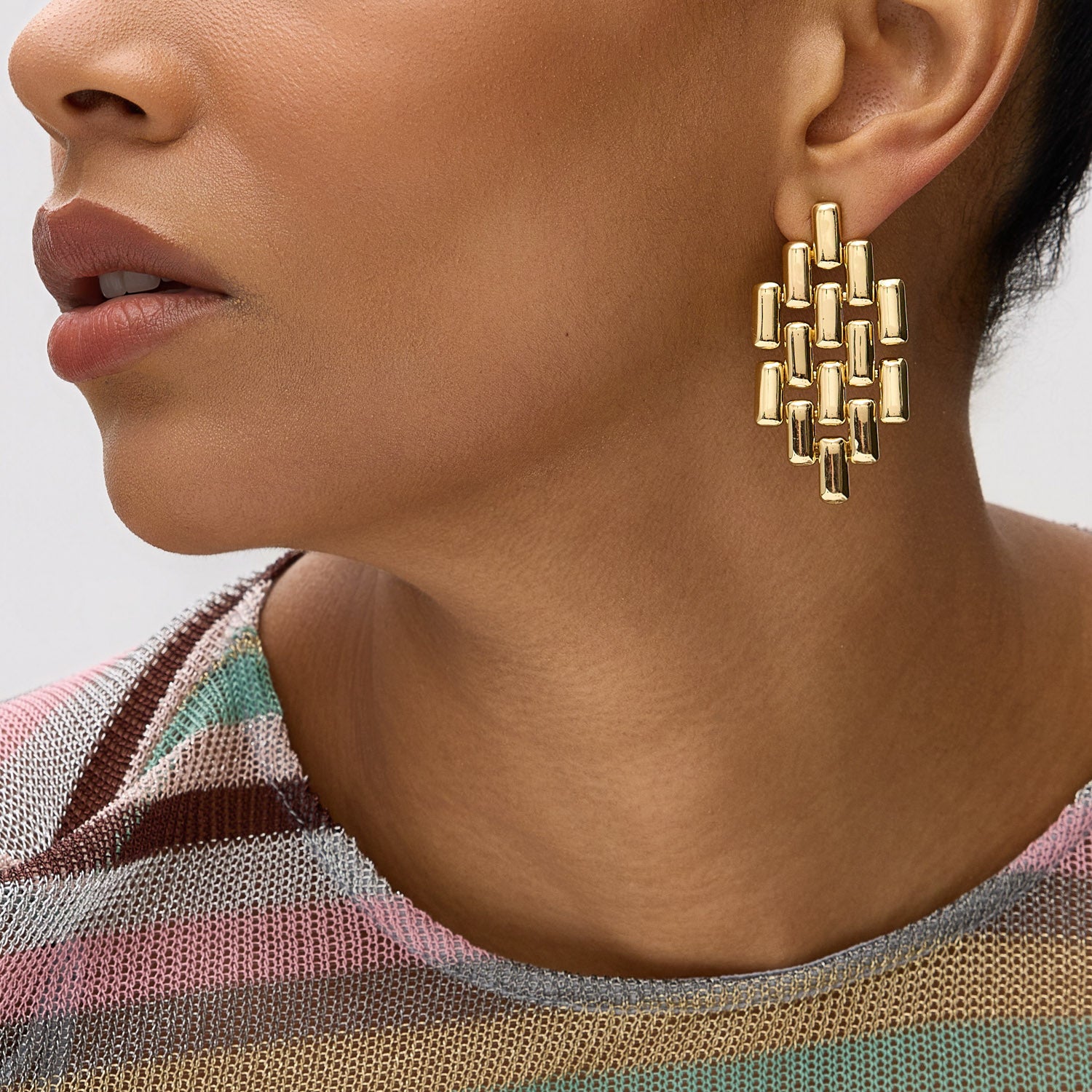 Close-up of a person wearing a gold geometric earring with a blurred background
