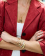 Person wearing a red coat with gold jewelry and red nail polish.