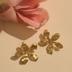 Gold Flower Studs on Cream Flat Surface with Pink Flower