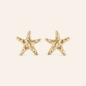 Hammered Gold Star Fish Stud Earrings on Cream Background