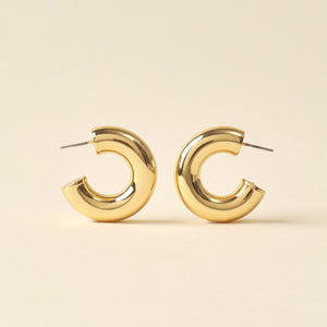 Gold Hoop Earrings on Tan Background