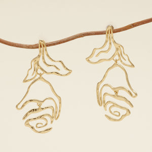 Gold Organic Shaped Flower Earrings Staged on Branch with Cream Background