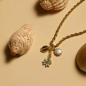 Multi-Charm Necklace Staged with Shells on Flat Cream Background