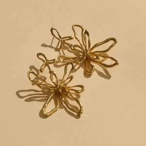 Gold Sculptural Flower Drop Earrings on Flat Cream Background
