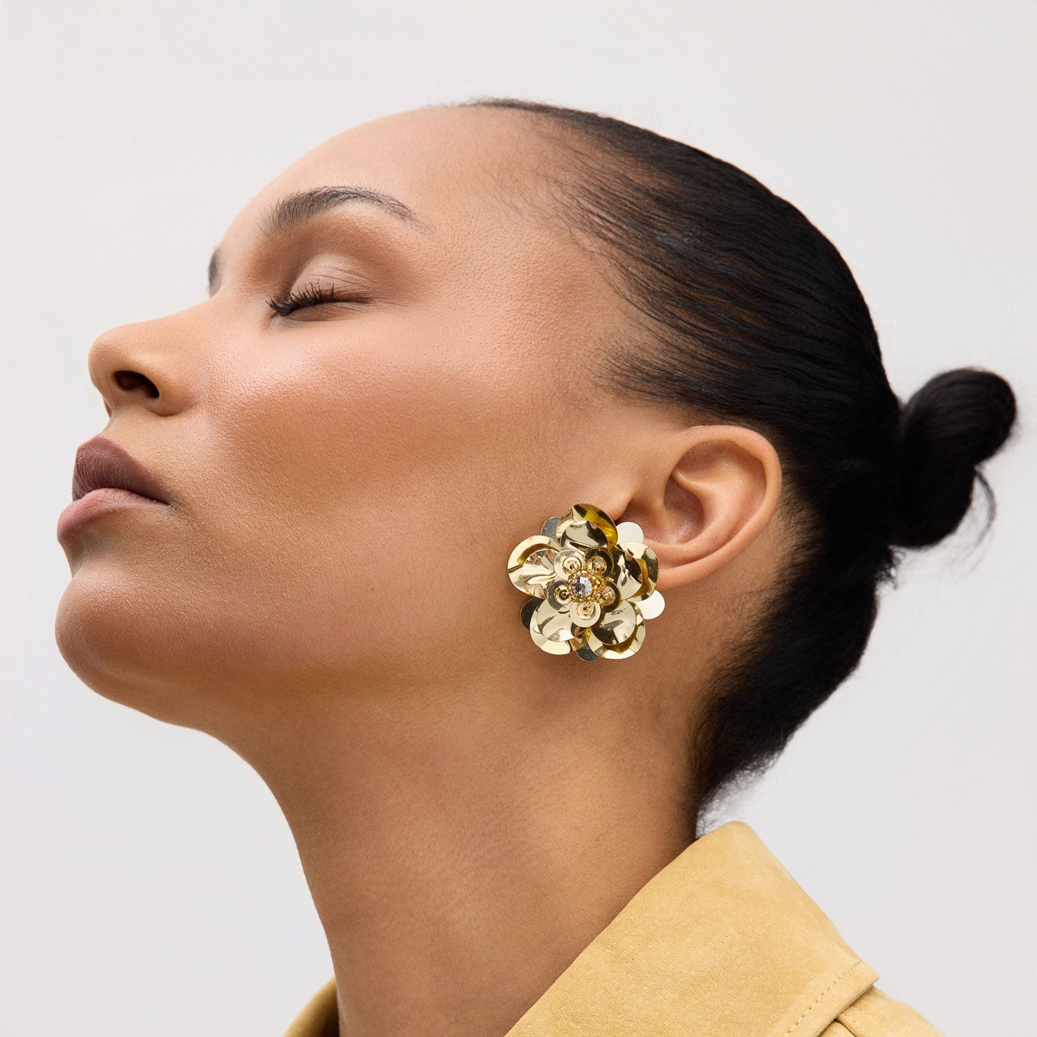 Woman wearing a floral earring with a neutral background