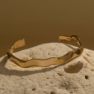 Gold Wavy Cuff Bracelet On Ivory Coral and Olive Green Background