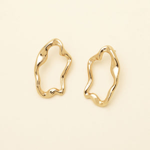 Gold Wavy Stud Earrings Staged on Cream Background