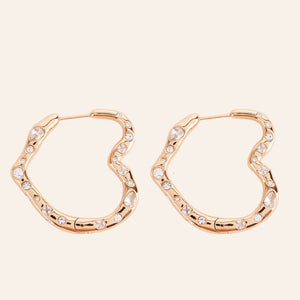 Gold and Crystal Heart Hoop Earrings on Cream Background