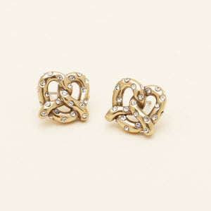 Gold and Crystal Pretzel Stud Earrings on Cream Background