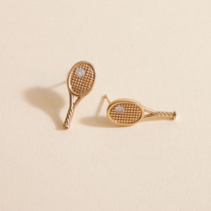 Gold and Crystal Tennis Racket Studs on Tan Background