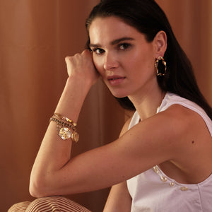 Gold and Pearl Charm Bracelet Styled on Model with Gold Cuff Bracelet and Gold Earrings