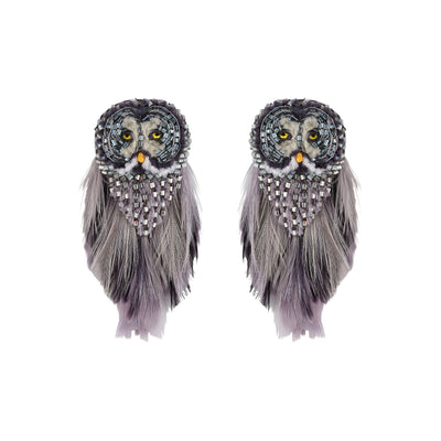 A pair of owl-shaped earrings made with gray and black feathers, silver rhinestones, and yellow eyes, shown against a plain white background.