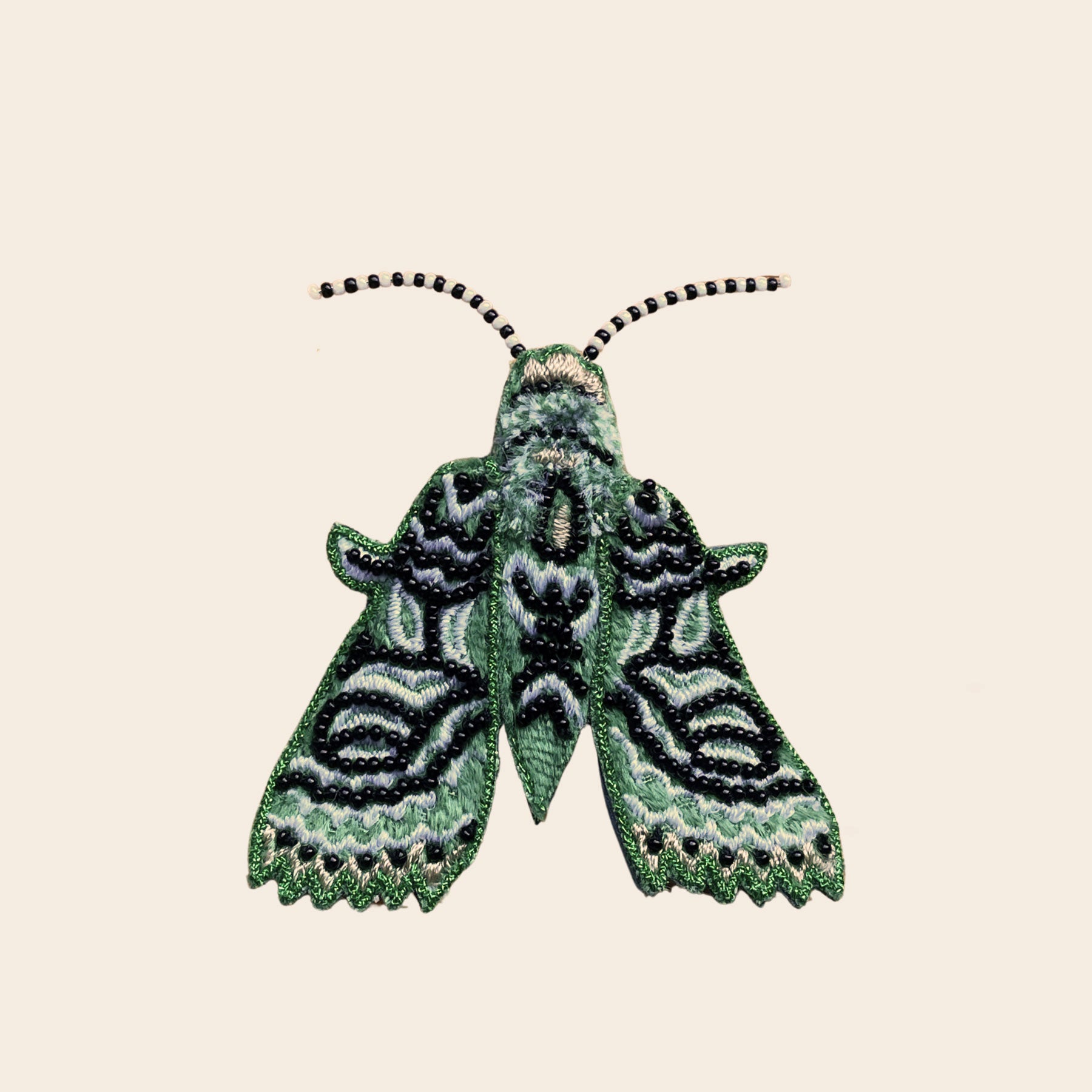 Black and Green Beaded Moth Brooch on Tan Background