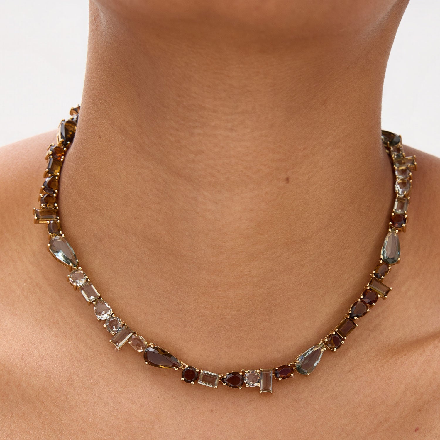 Necklace with gemstones worn by a person on a neutral background