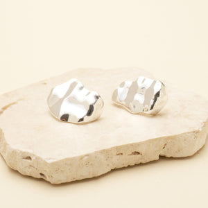 Silver Organic Shaped Stud Earrings Styled on Stone with Cream Background