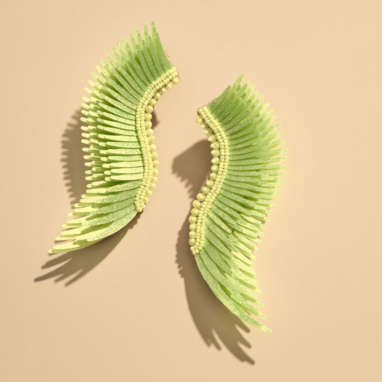 Sparkly Lime Sequin and Bead Wing Earrings on Flat Tan Background