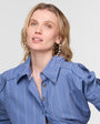 Woman wearing a blue pinstripe shirt against a plain background
