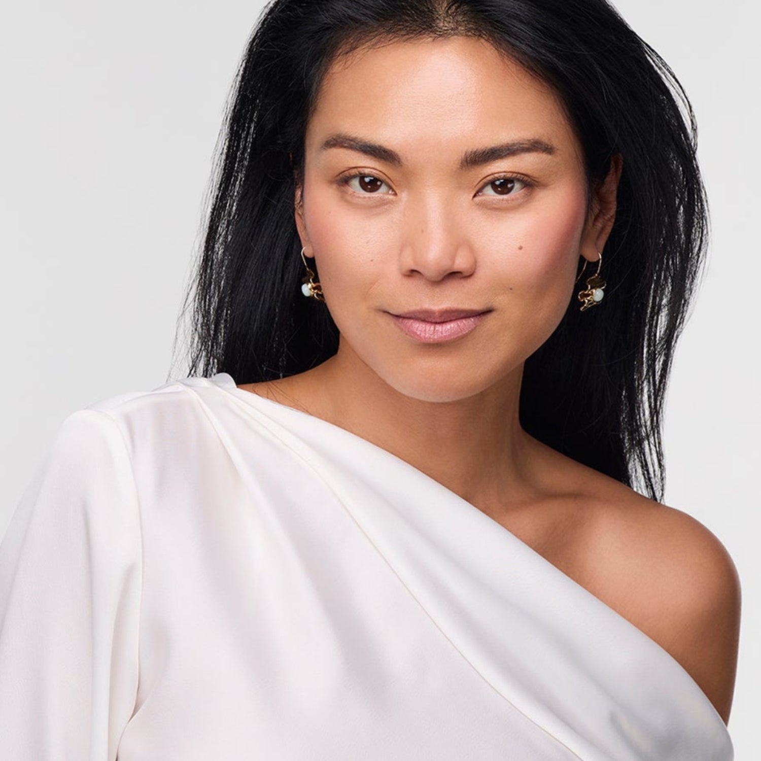 Woman wearing a white off-shoulder top against a plain background