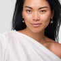 Woman wearing a white off-shoulder top against a plain background