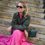 Teal feather drop earrings with gold-tone and green beaded details On Mignonne Gavigan Lifestyle Shot Sitting on stairs 