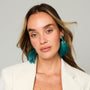 Teal feather drop earrings with gold-tone and green beaded details on model straight on 