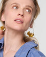 Woman wearing gold earrings with a plain background