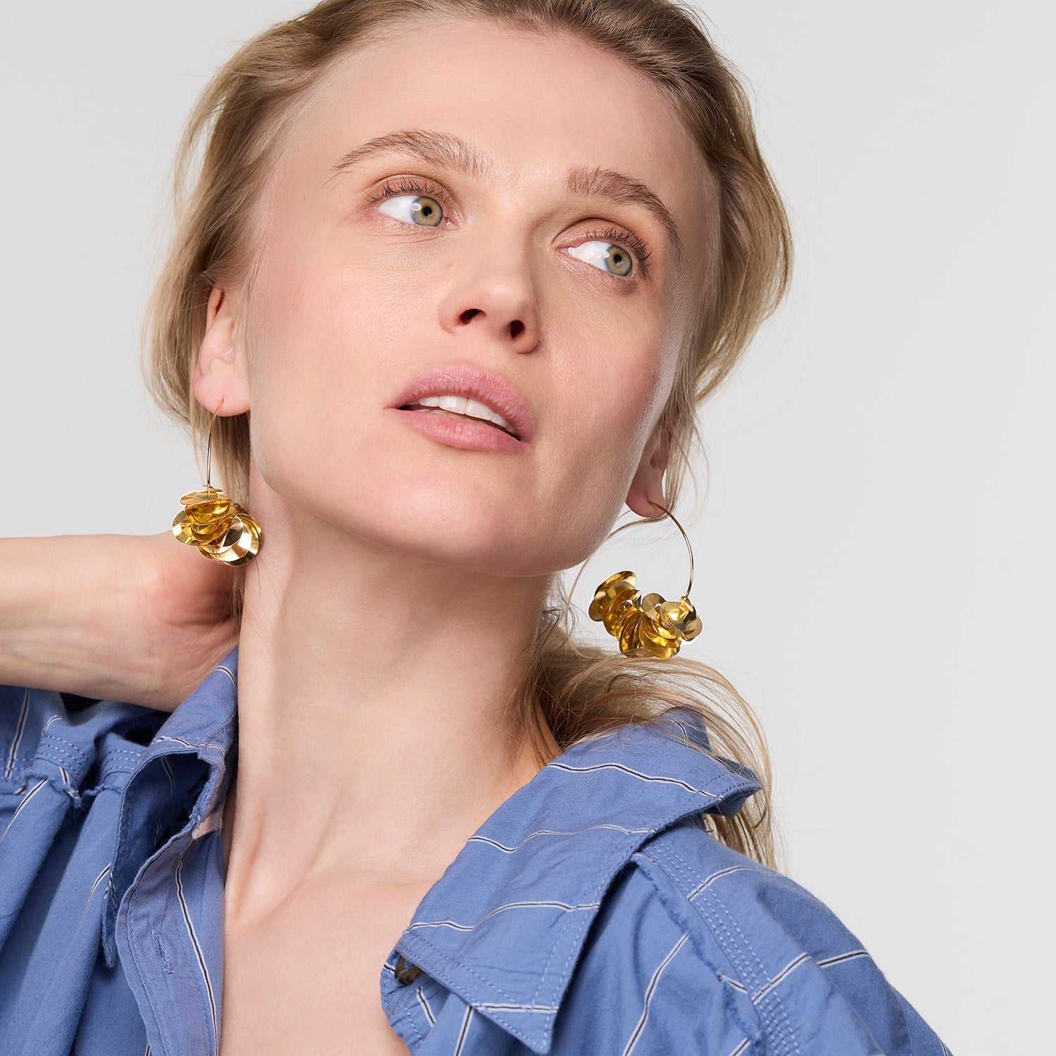 Woman wearing gold earrings with a plain background