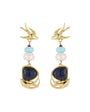 A pair of gold-tone dangle earrings featuring a swallow motif at the top, accented with light blue and white beads, and a large dark blue lapis lazuli-style stone in a wave-like gold setting at the bottom.