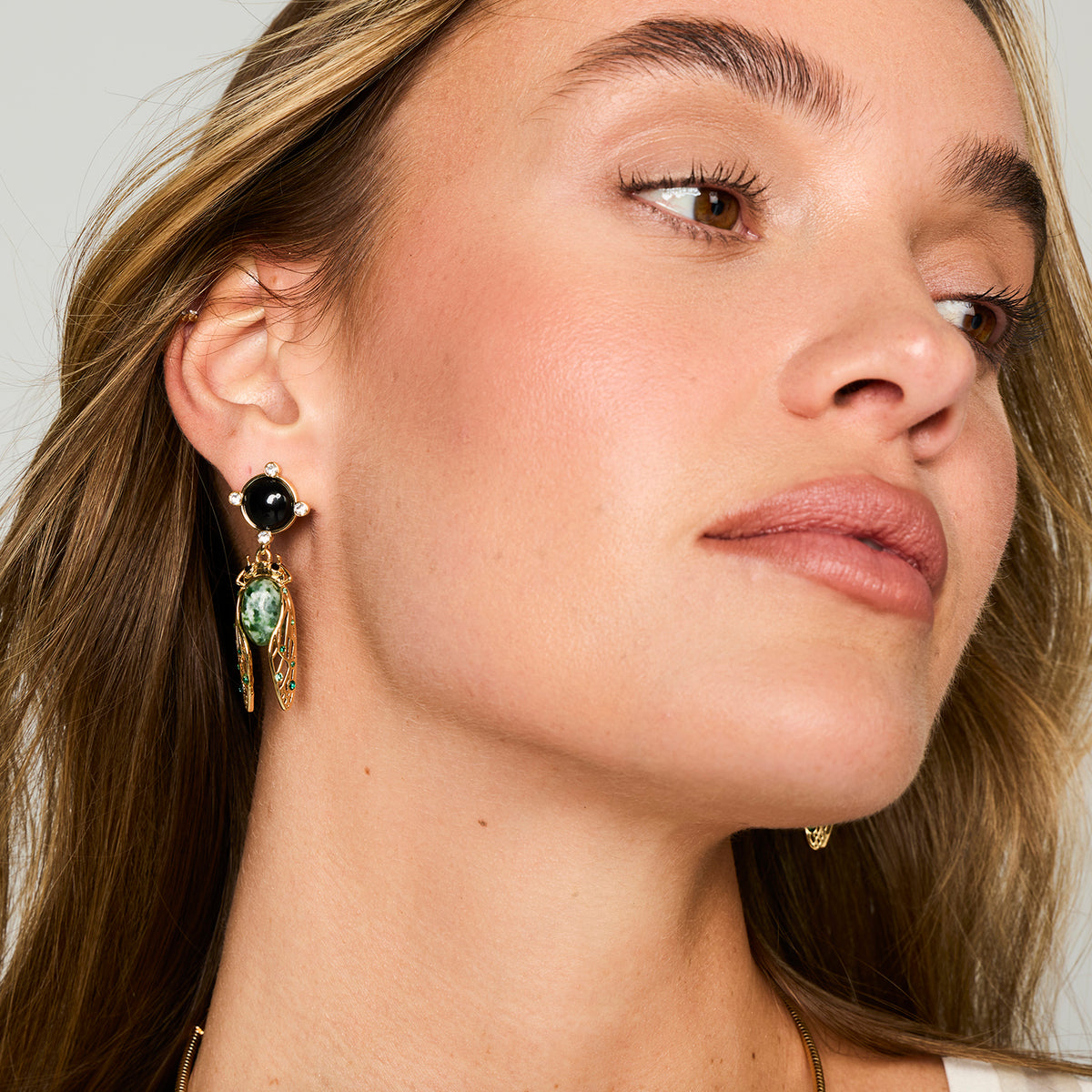 Cicada Inspired Black, Gold and Green dangle earrings on model 