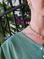 Person wearing a gold chain necklace with a blurred background