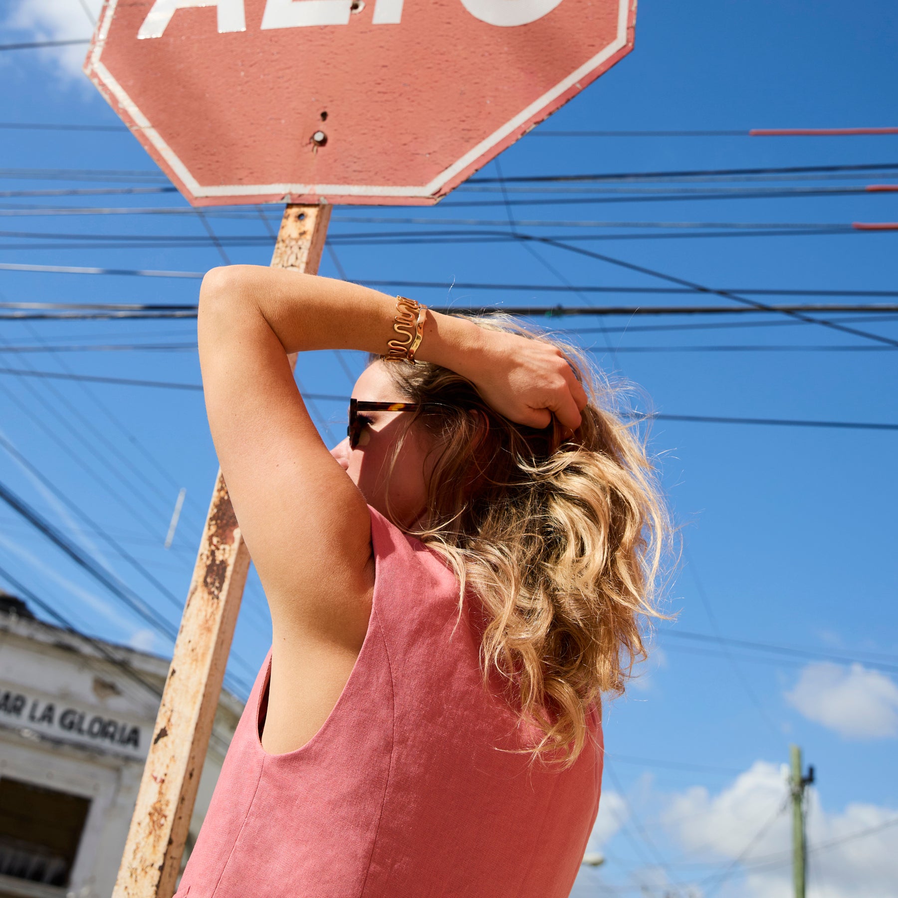 Model wearing pink vest outside with gold gold on wrist