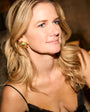 Model wearing black dress with gold and turquoise starburst earring