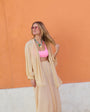 Model wearing colorful shell necklace in peach set with orange background